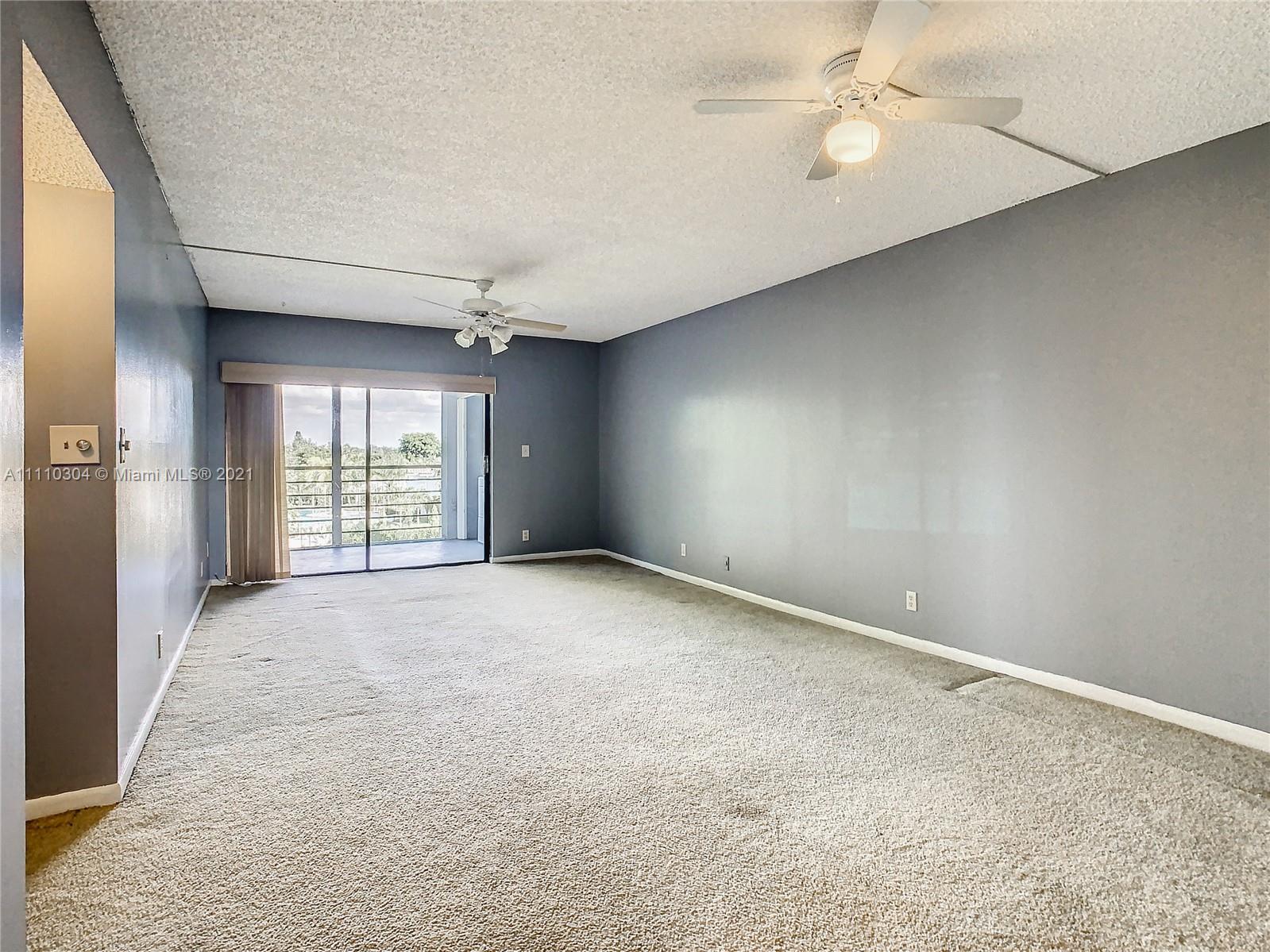 9235 Southwest 8th Street, Unit 401 Boca Raton, FL 33428 - Photo 11 of 40 an empty room with windows and fan