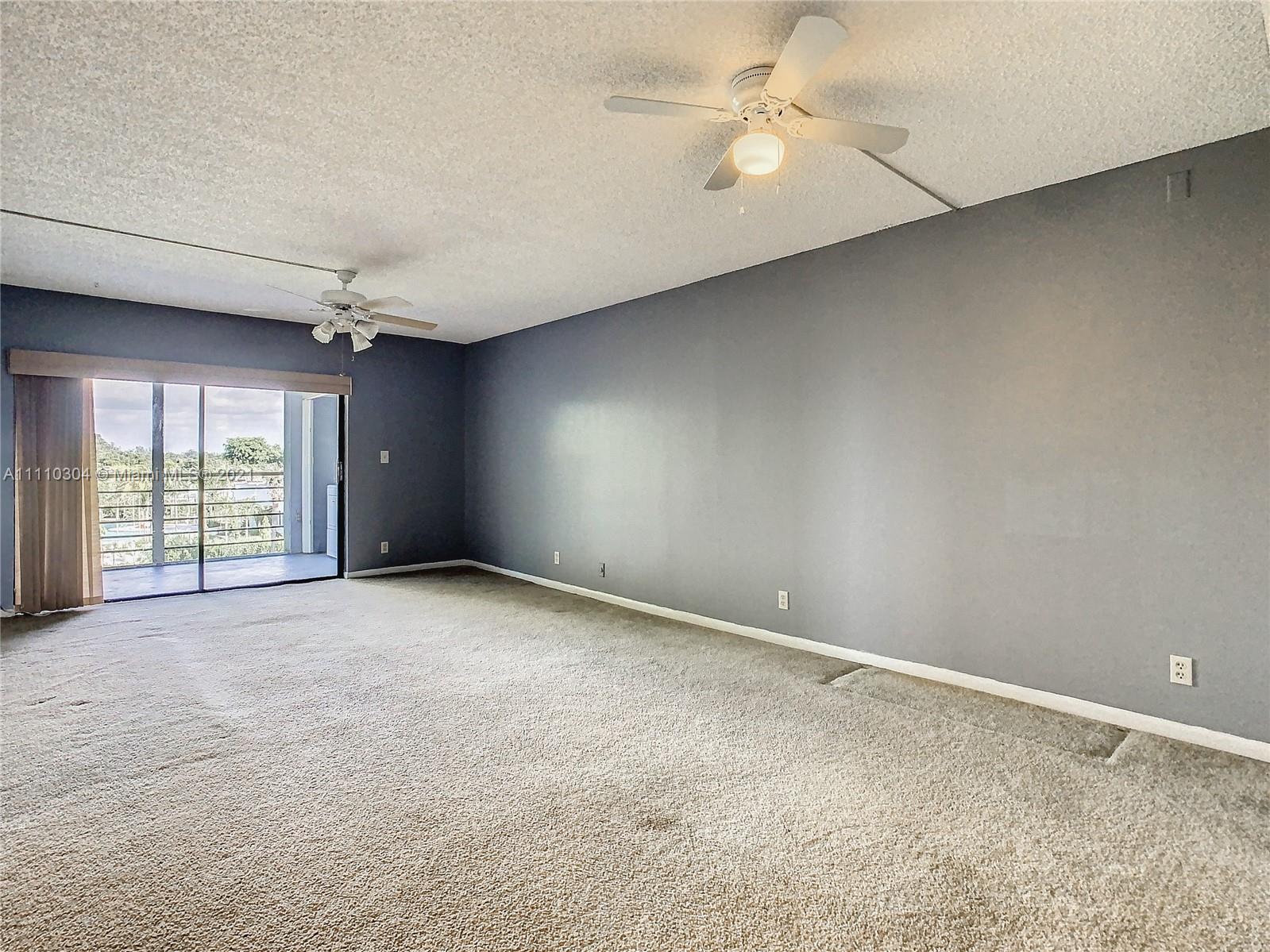 9235 Southwest 8th Street, Unit 401 Boca Raton, FL 33428 - Photo 13 of 40 an empty room with windows and ceiling fan