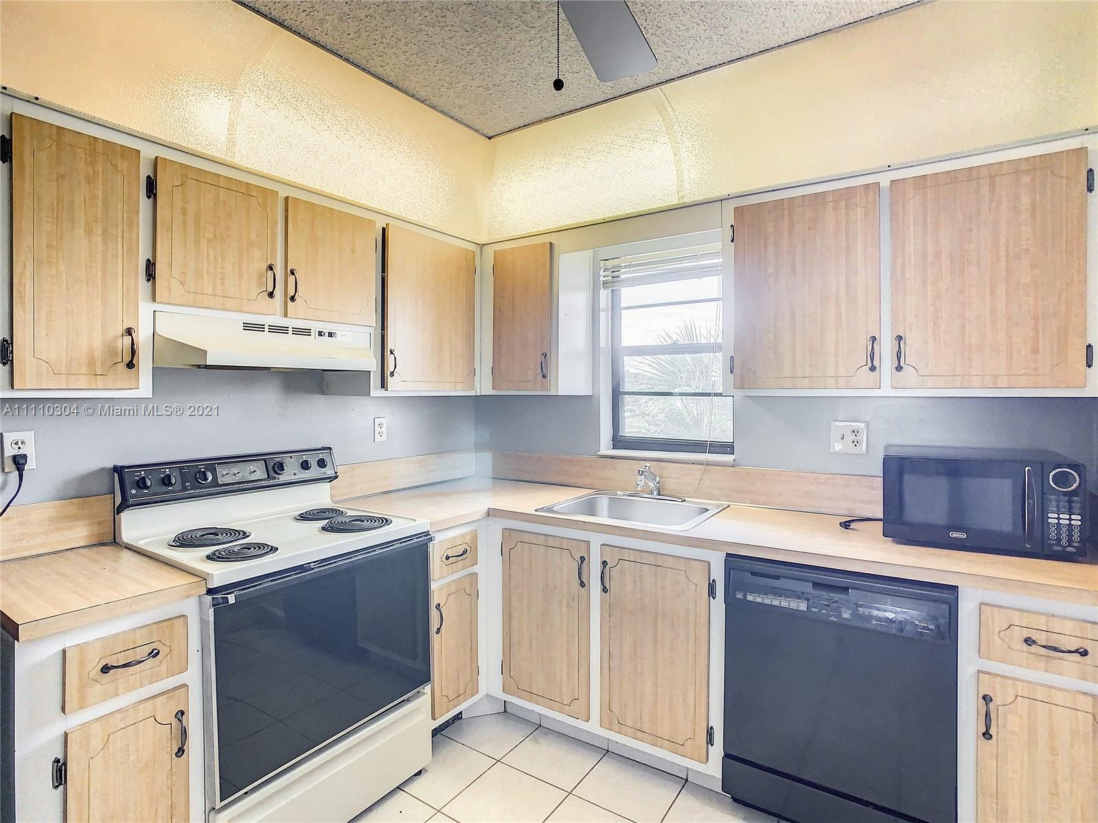 9235 Southwest 8th Street, Unit 401 Boca Raton, FL 33428 - Photo 17 of 40 a kitchen with cabinets appliances a sink and a window