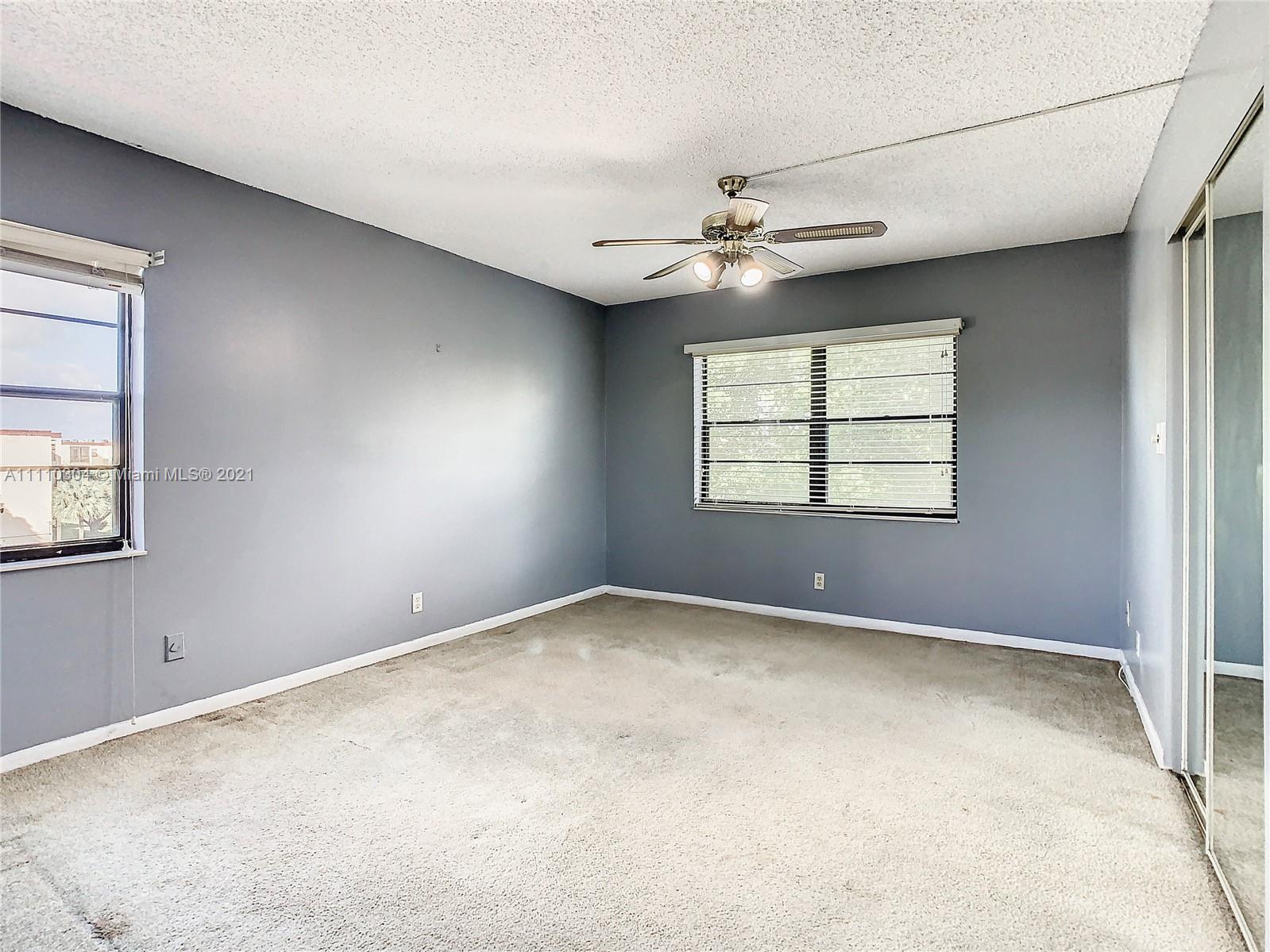 9235 Southwest 8th Street, Unit 401 Boca Raton, FL 33428 - Photo 23 of 40 an empty room with windows and ceiling fan