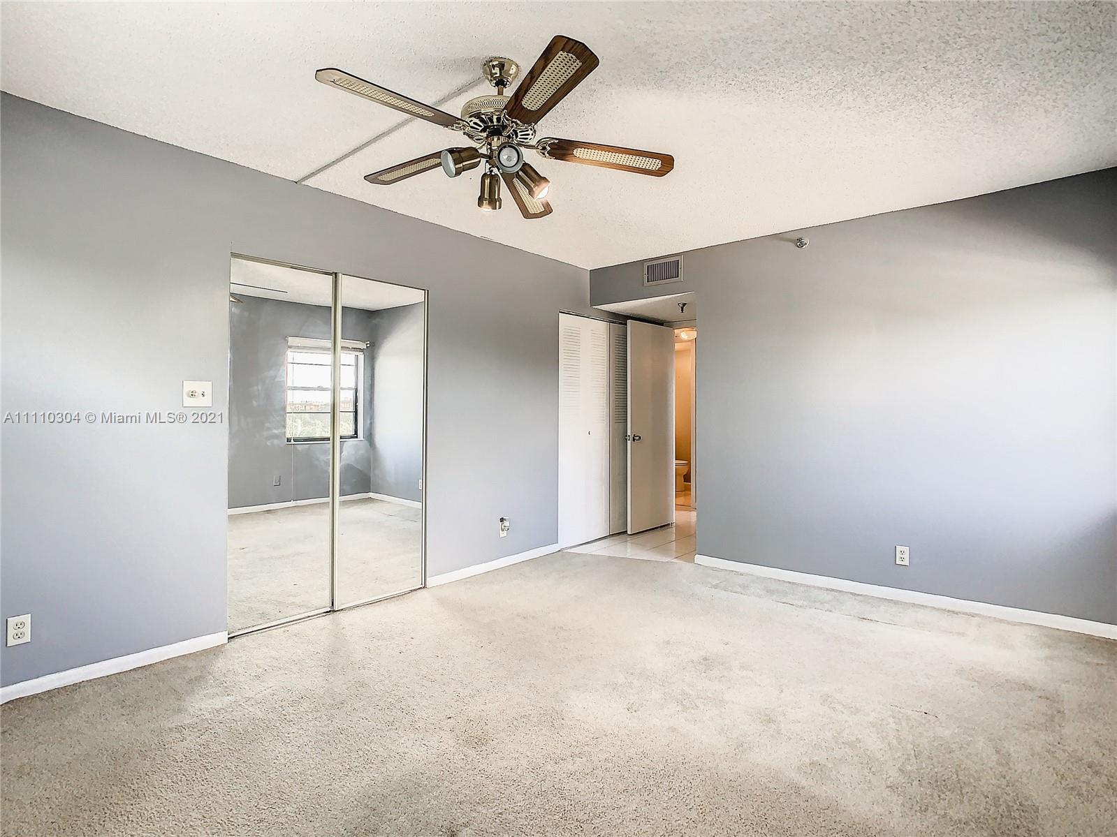 9235 Southwest 8th Street, Unit 401 Boca Raton, FL 33428 - Photo 26 of 40 an empty room with a chandelier fan and windows