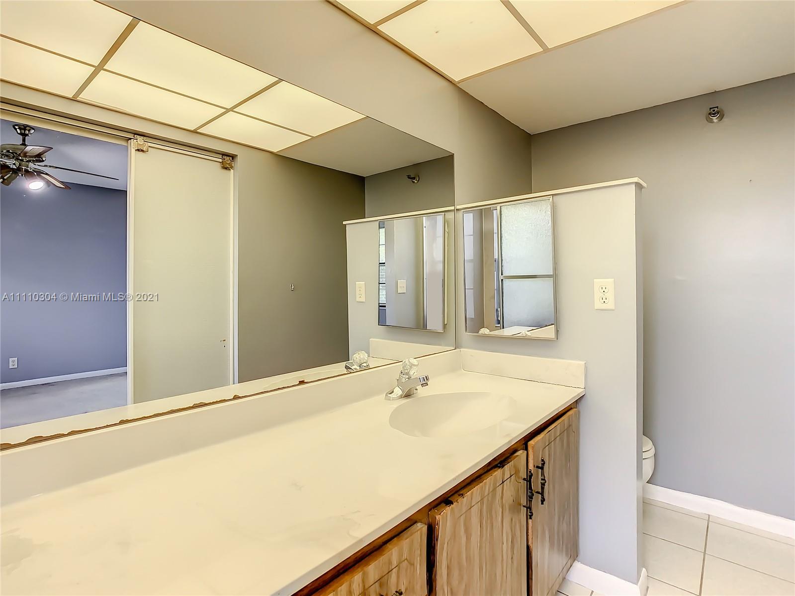 9235 Southwest 8th Street, Unit 401 Boca Raton, FL 33428 - Photo 29 of 40 a bathroom with a sink and a mirror