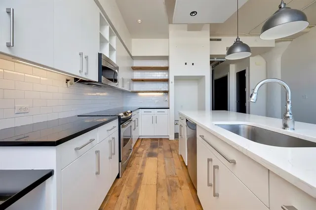a kitchen with stainless steel appliances granite countertop a sink and a stove top oven