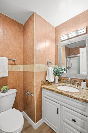 a bathroom with a granite countertop toilet sink and mirror
