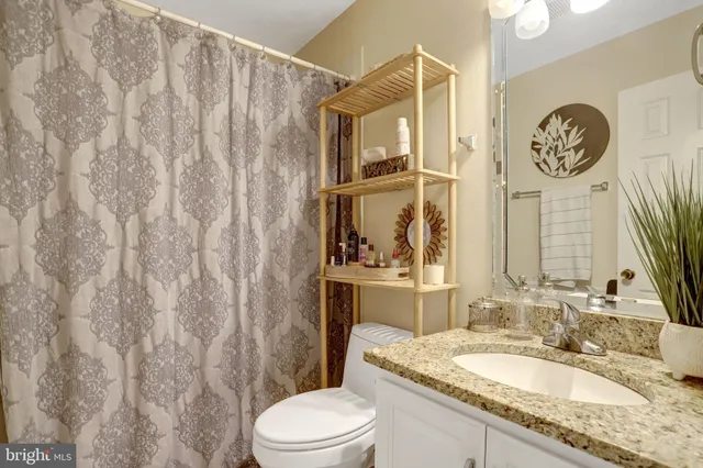 a bathroom with a granite countertop sink mirror vanity and toilet