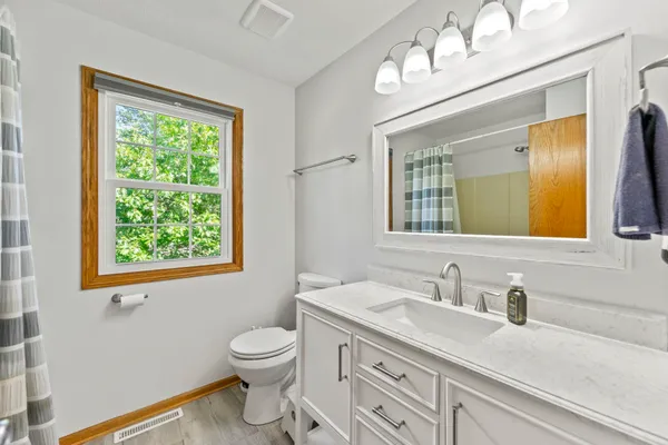 a bathroom with a granite countertop sink toilet a large mirror and a window