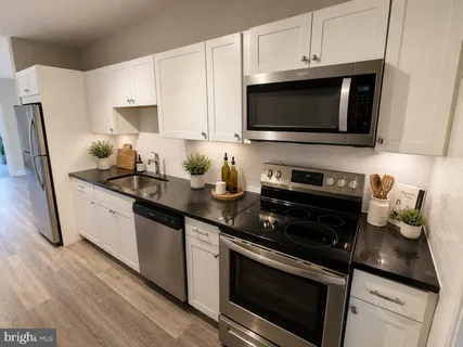 a kitchen with stainless steel appliances a stove a microwave a sink and cabinets