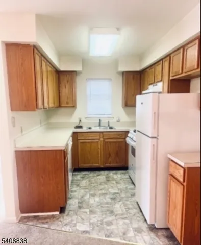 a kitchen with a refrigerator a stove top oven a sink and cabinets