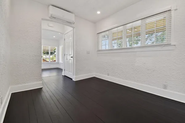 an empty room with wooden floor and windows