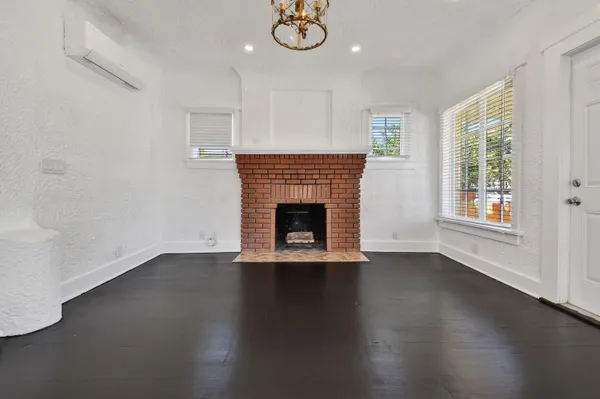 an empty room with wooden floor a fireplace and windows