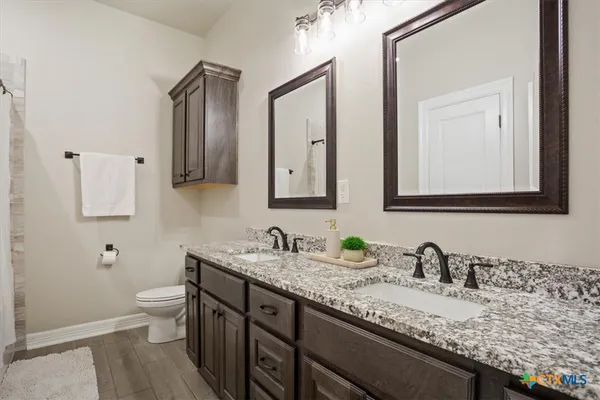 a bathroom with a granite countertop sink a toilet and mirror