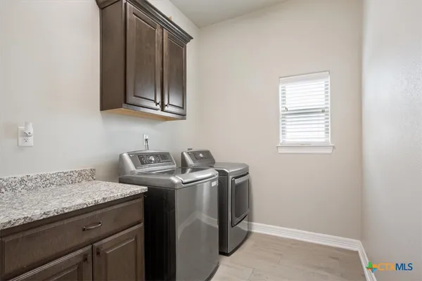 a utility room with granite countertop cabinets washer and dryer