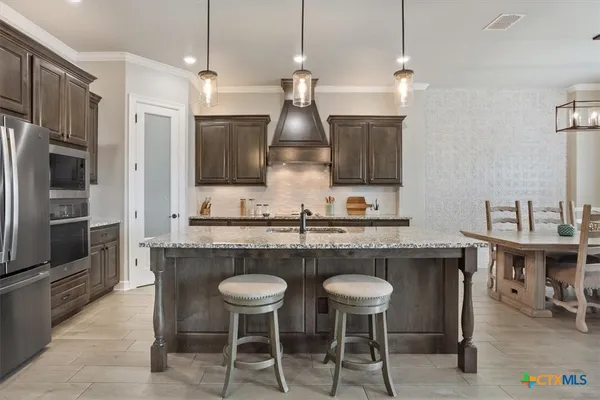 a kitchen with stainless steel appliances granite countertop a kitchen island a stove and a refrigerator