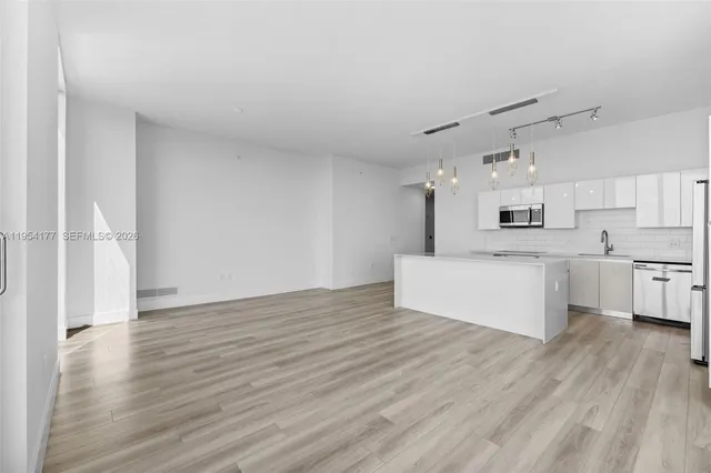 a large kitchen with kitchen island a large counter top space a sink stainless steel appliances and cabinets