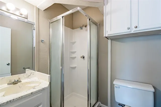 a bathroom with a granite countertop sink and mirror with toilet