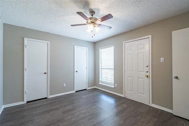 an view of an empty room with wooden floor and a ceiling fan
