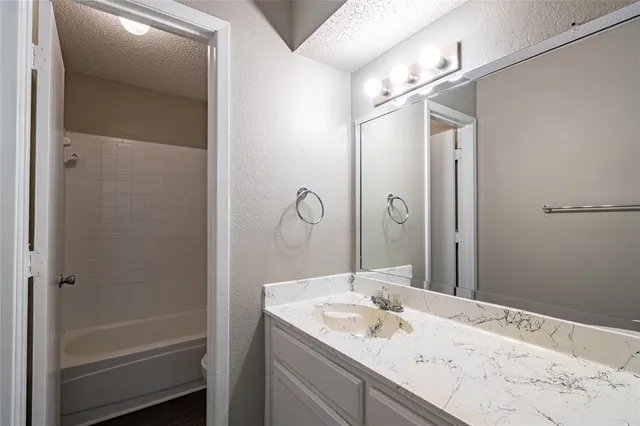 a bathroom with a granite countertop sink mirror and a shower