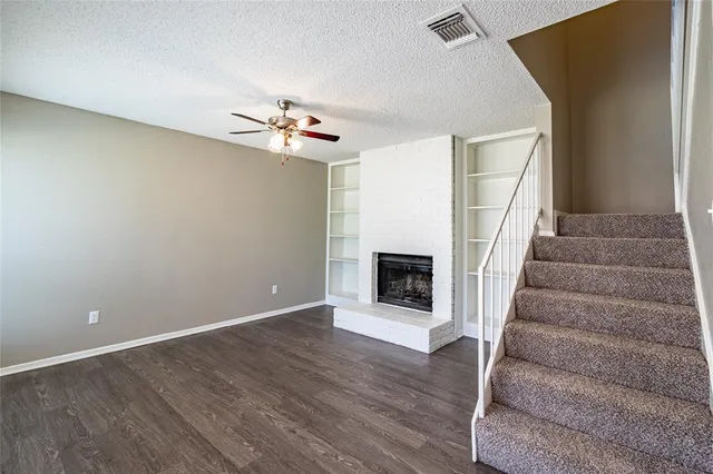 a view of an empty room with wooden floor and a fireplace