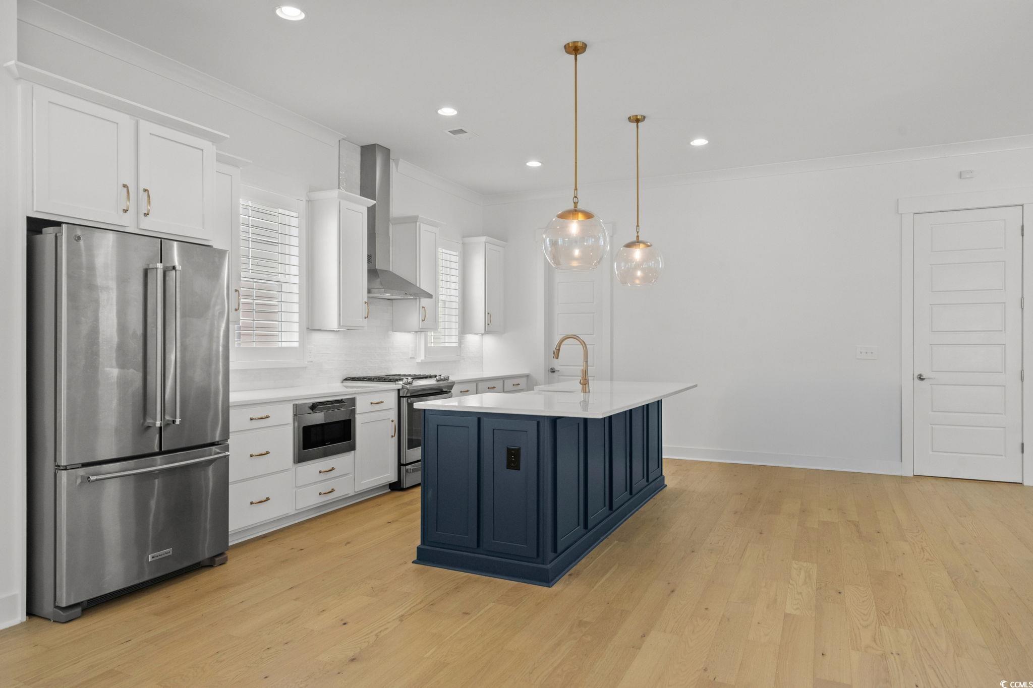 477 Ayrhill Loop Myrtle Beach, SC 29588 - Photo 11 of 39 Kitchen with white cabinetry, stainless steel appliances, crown molding, hanging light fixtures, and light wood-type flooring