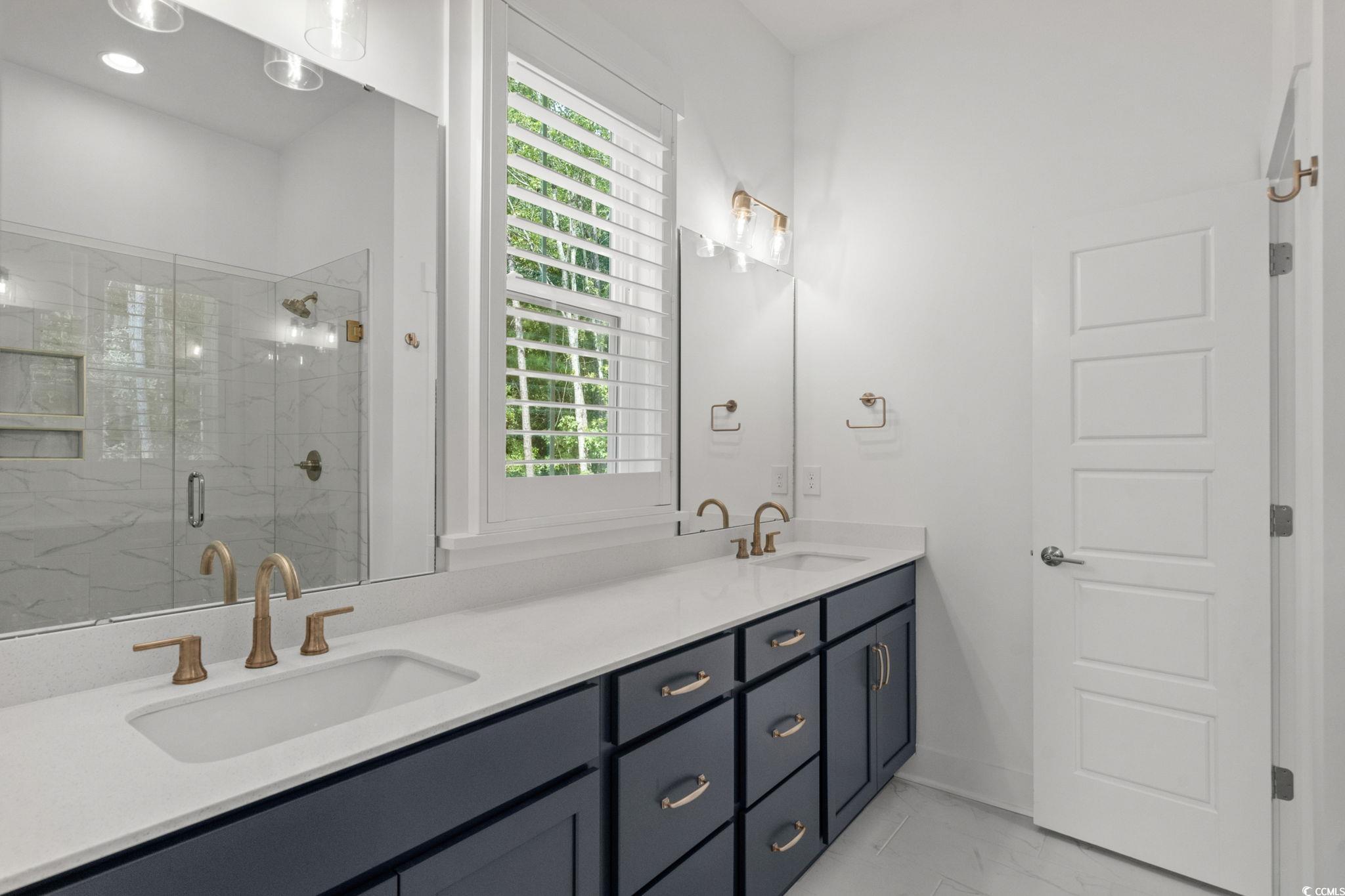 477 Ayrhill Loop Myrtle Beach, SC 29588 - Photo 22 of 39 Bathroom with double vanity, a stall shower, and light marble finish flooring