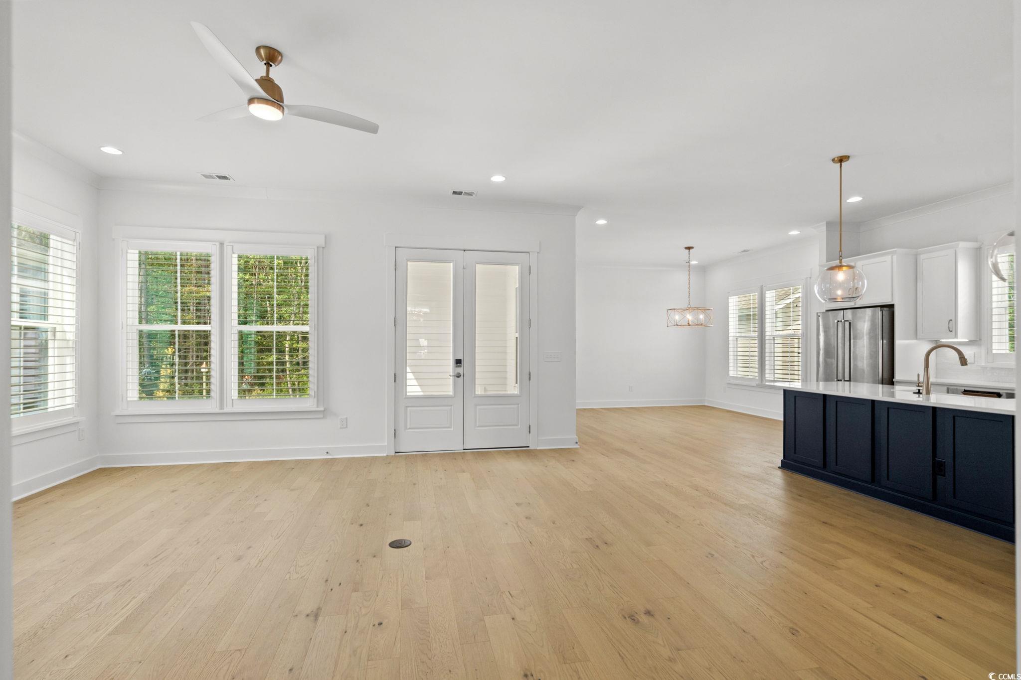 477 Ayrhill Loop Myrtle Beach, SC 29588 - Photo 5 of 39 Unfurnished living room with light wood finished floors, crown molding, ceiling fan, recessed lighting, and french doors