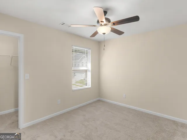 an empty room with windows and fan