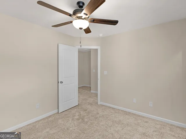 an empty room with a fan & a ceiling fan