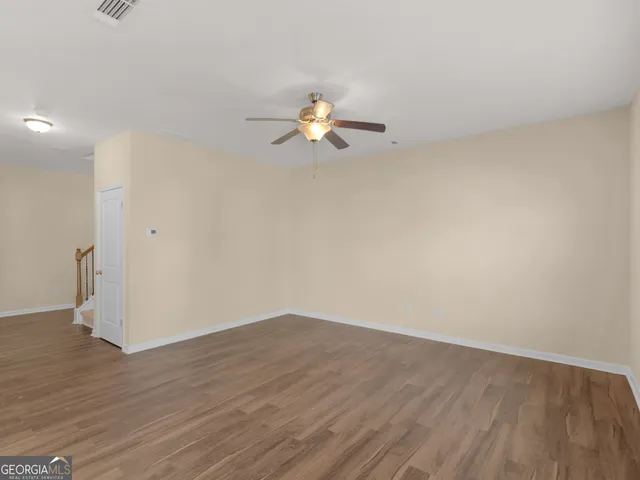a view of a room with wooden floor and a ceiling fan