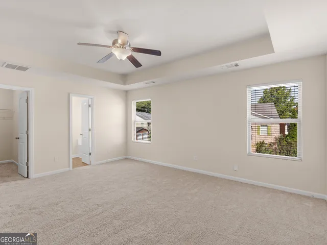 an empty room with windows and fan