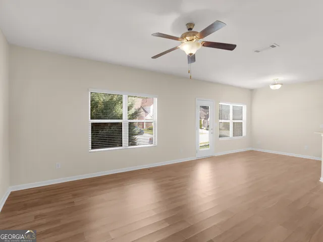 a view of an empty room with wooden floor and a window