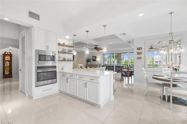a kitchen with stainless steel appliances kitchen island granite countertop a table chairs sink and cabinets