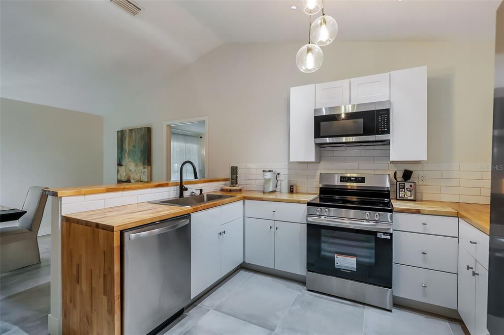 3222 Southwest 27th Street Gainesville, FL 32608 - Photo 9 of 42 a kitchen with stainless steel appliances a stove sink microwave and cabinets