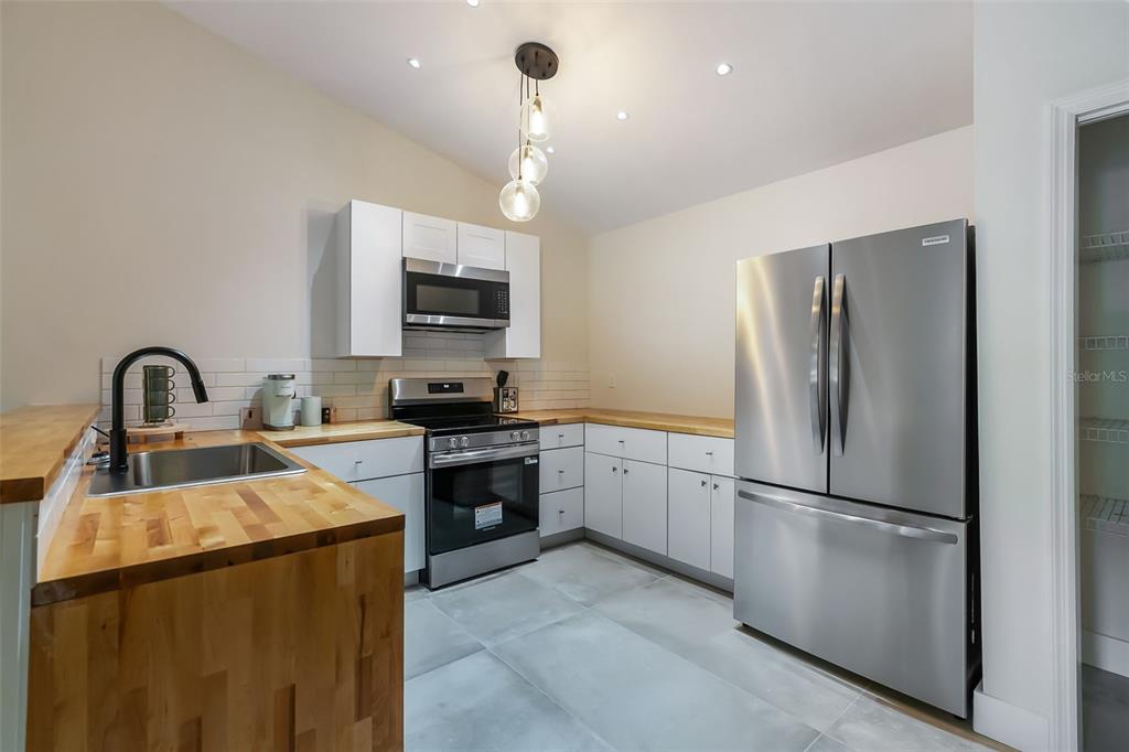 3222 Southwest 27th Street Gainesville, FL 32608 - Photo 10 of 42 a kitchen with granite countertop a refrigerator and a stove top oven