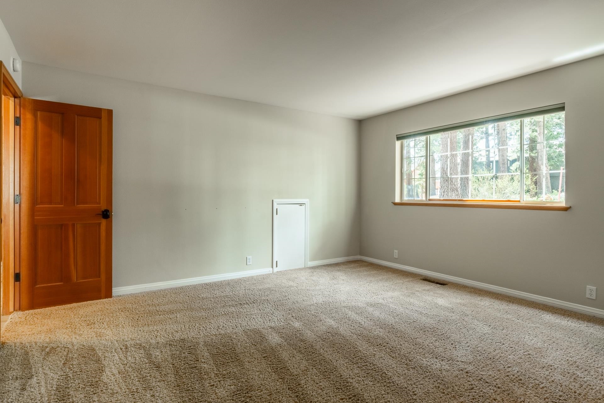 272 Ridge Way Mammoth Lakes, CA 93546 - Photo 39 of 55 Spacious room featuring neutral carpeting, light gray walls, a large window with a wood sill, and a natural wood-paneled door
