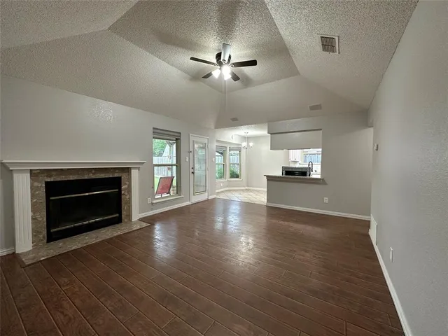 an empty room with wooden floor fireplace and windows