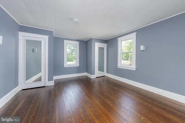 an empty room with wooden floor and windows