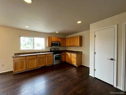 a kitchen with stainless steel appliances granite countertop a stove a sink and a refrigerator with wooden floor