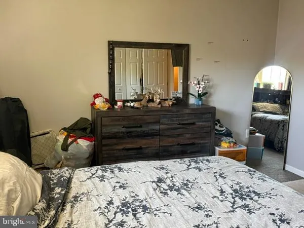 a bed room with a bed mirror and a chair