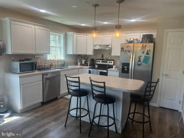 a kitchen with stainless steel appliances a dining table chairs stove refrigerator and cabinets