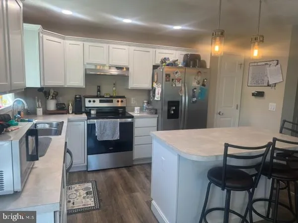 a large kitchen with stainless steel appliances granite countertop a stove a refrigerator a sink a dining table and chairs