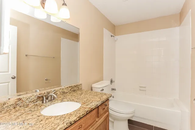 a bathroom with a granite countertop sink a toilet a mirror and shower