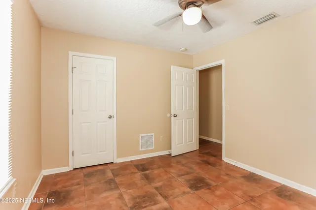 a view of an empty room and chandelier fan