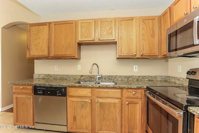 a kitchen with stainless steel appliances granite countertop a sink stove and microwave