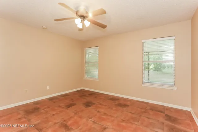 an empty room with windows and fan