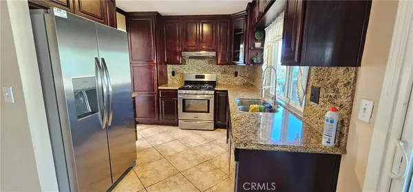 a kitchen with stainless steel appliances granite countertop a refrigerator a stove and a sink