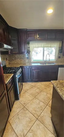 a kitchen with stainless steel appliances granite countertop a stove a sink and a microwave