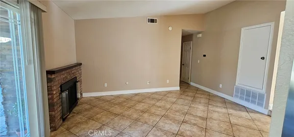 a view of an empty room with a fireplace and a window