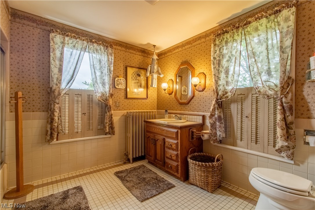 18752 Courtney Road Beloit, OH 44609 - Photo 18 of 23 Bathroom featuring radiator, mirror, light tile floors, oversized vanity, and partially tiled walls