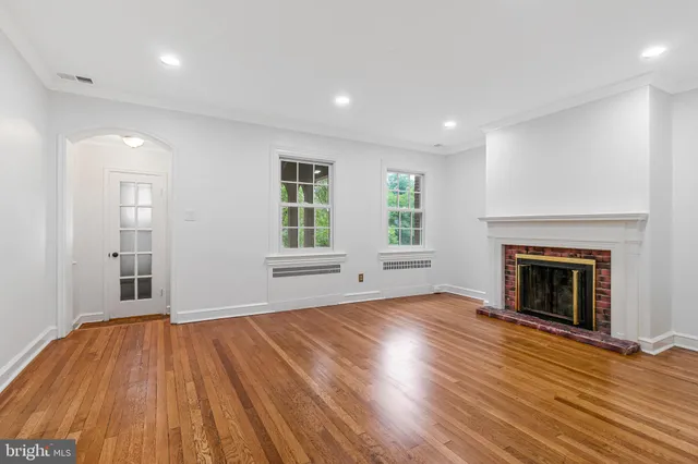 an empty room with wooden floor fireplace and windows