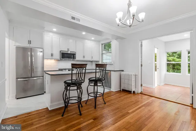 a kitchen with stainless steel appliances granite countertop a refrigerator oven a stove a dining table and chairs with wooden floor